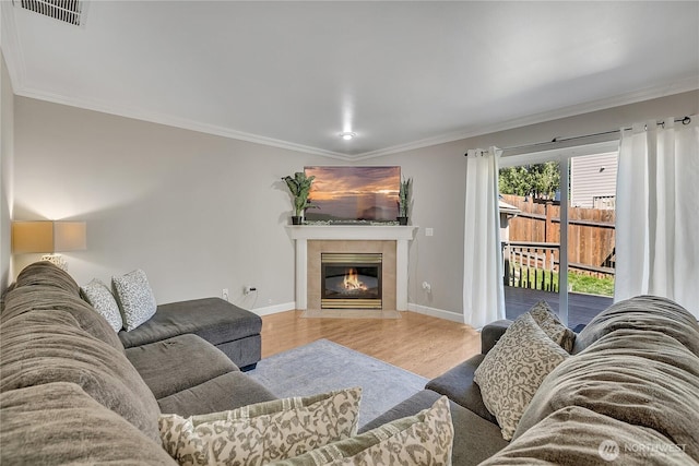 living area featuring wood finished floors, crown molding, a fireplace, and baseboards