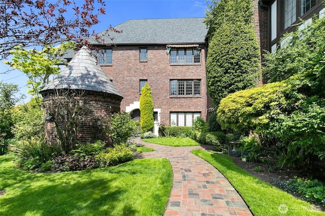 back of house featuring brick siding and a yard