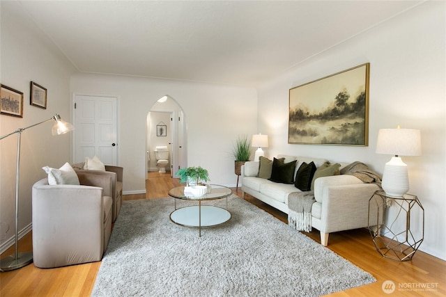living area with arched walkways and wood finished floors