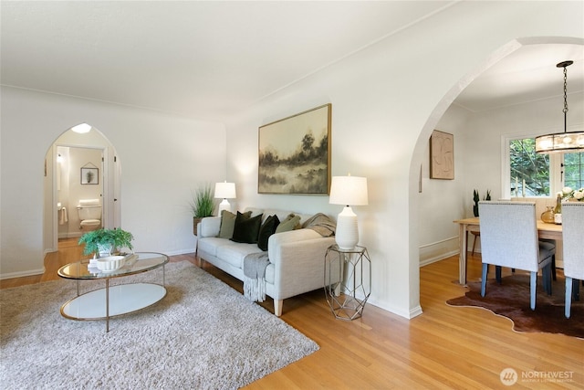 living room with baseboards, arched walkways, and wood finished floors