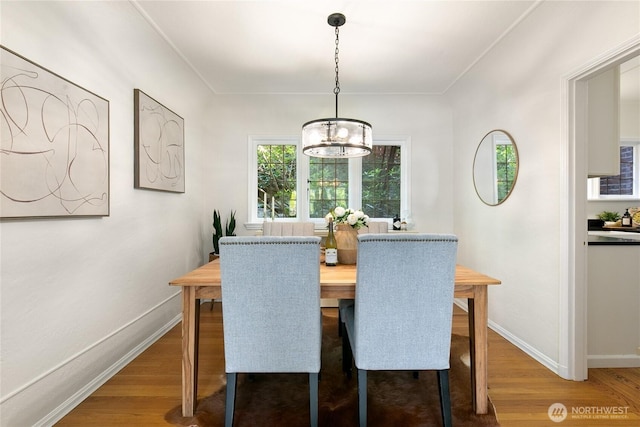 dining room featuring baseboards, wood finished floors, and a notable chandelier