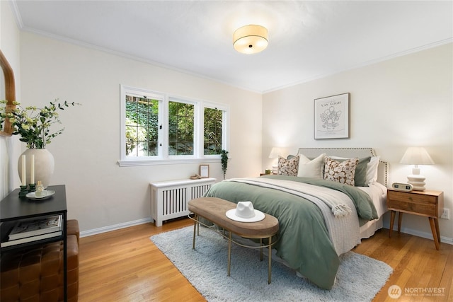 bedroom featuring radiator heating unit, baseboards, crown molding, and light wood finished floors
