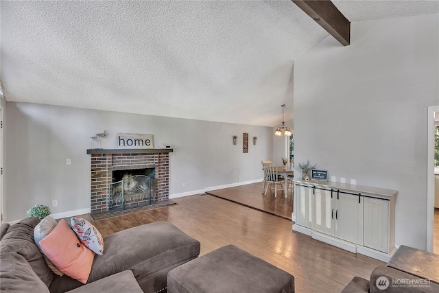791 NE Pinecrest Dr, Bremerton, WA 98311 - living room featuring wood finished floors, a textured ceiling, a fireplace, a chandelier, and baseboards