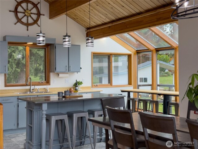 34A Saratoga Dr, Hat Island, WA 98206 - interior space featuring pendant lighting, a kitchen island, vaulted ceiling with beams, wood ceiling, and a sink