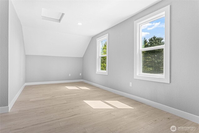 additional living space with light wood-type flooring, baseboards, and lofted ceiling