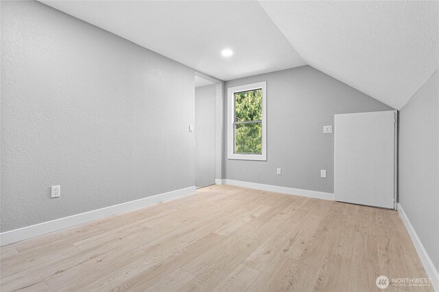 bonus room with light wood-type flooring, baseboards, and lofted ceiling