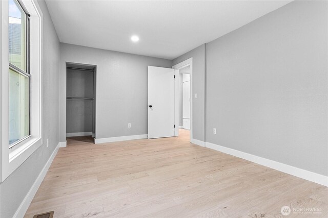 unfurnished bedroom with baseboards, light wood finished floors, and multiple windows
