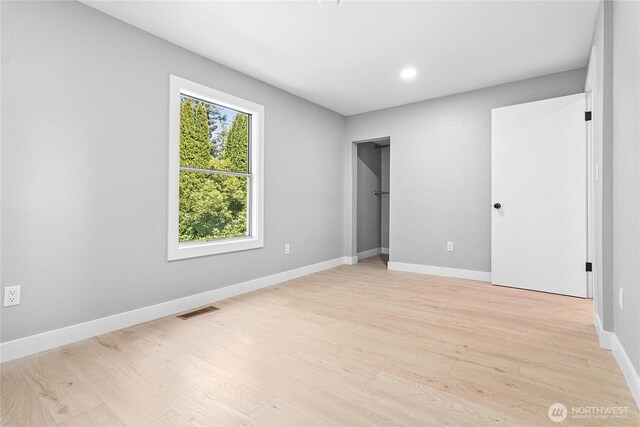 unfurnished bedroom with visible vents, light wood-style floors, and baseboards