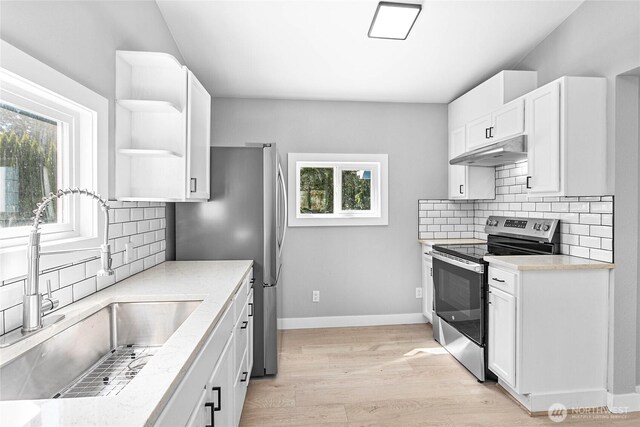 kitchen with a sink, under cabinet range hood, a wealth of natural light, and stainless steel appliances