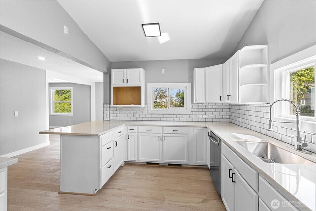 kitchen featuring open shelves, a peninsula, white cabinets, a sink, and vaulted ceiling