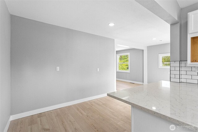 empty room featuring recessed lighting, baseboards, and light wood-style flooring