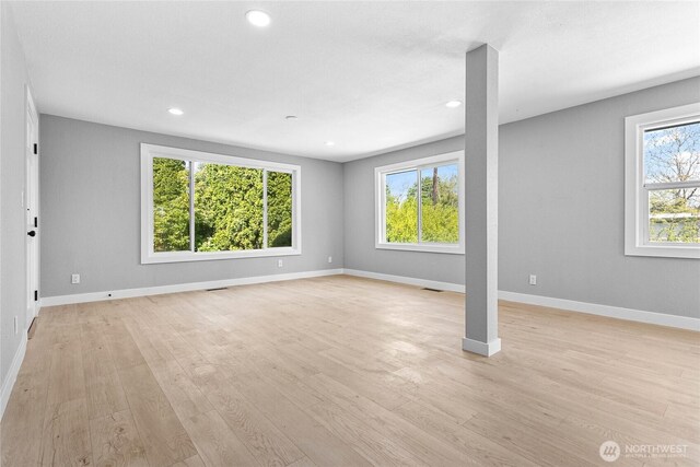 unfurnished living room featuring baseboards, recessed lighting, light wood-style flooring, and a wealth of natural light