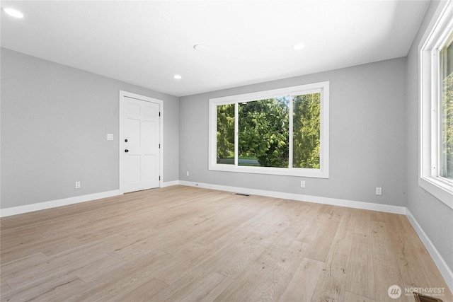 spare room with light wood-style floors, baseboards, a healthy amount of sunlight, and visible vents