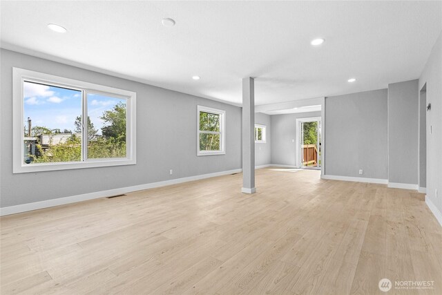 unfurnished living room with recessed lighting, baseboards, light wood finished floors, and a wealth of natural light