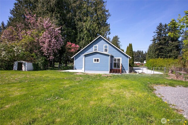 back of house with a lawn, fence, a shed, and entry steps