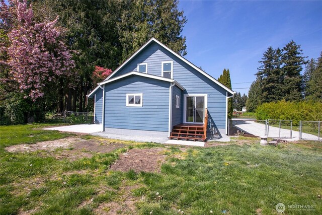 rear view of property featuring a lawn, fence, and a patio