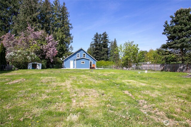 view of yard with an outdoor structure, fence, and a shed