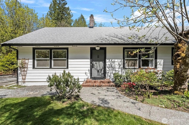 view of front of property with a shingled roof and a chimney