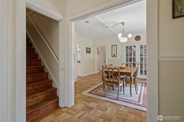 dining space featuring a chandelier, french doors, and stairway
