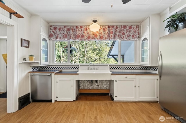 kitchen featuring dark countertops, stainless steel appliances, light wood-style flooring, and visible vents