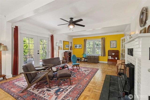 interior space featuring french doors, ornamental molding, a fireplace, and a ceiling fan