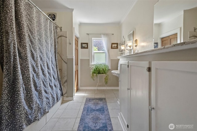 full bath featuring tile patterned flooring, crown molding, vanity, curtained shower, and a wainscoted wall