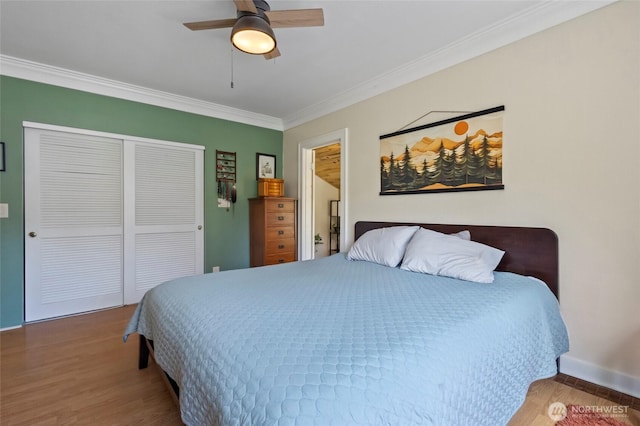 bedroom with crown molding, a closet, wood finished floors, baseboards, and a ceiling fan