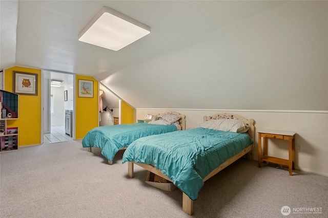bedroom featuring ensuite bathroom, carpet, and lofted ceiling