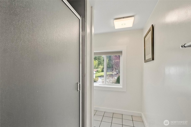 corridor with baseboards and light tile patterned flooring