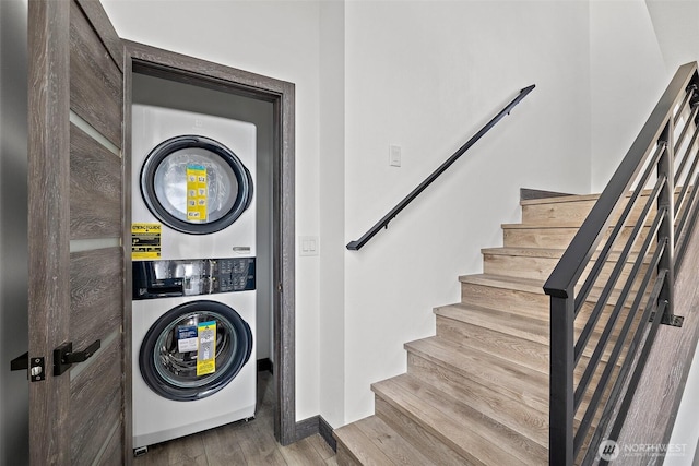 laundry room featuring laundry area, stacked washing maching and dryer, and wood finished floors