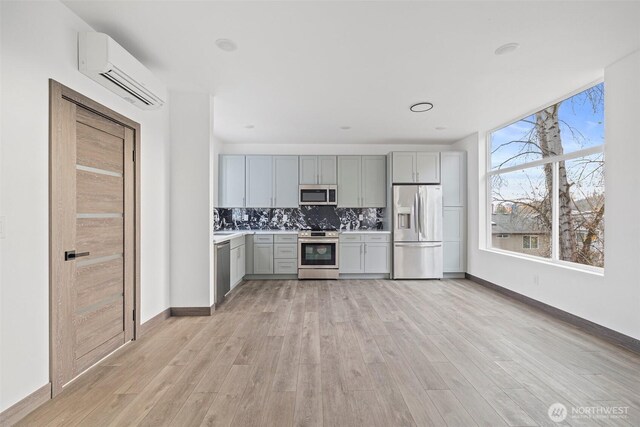 9751 57th Ave S, Seattle, WA 98118 - kitchen with light countertops, an AC wall unit, light wood-style flooring, stainless steel appliances, and gray cabinetry