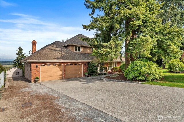 view of front of home featuring driveway, a chimney, roof with shingles, a garage, and brick siding