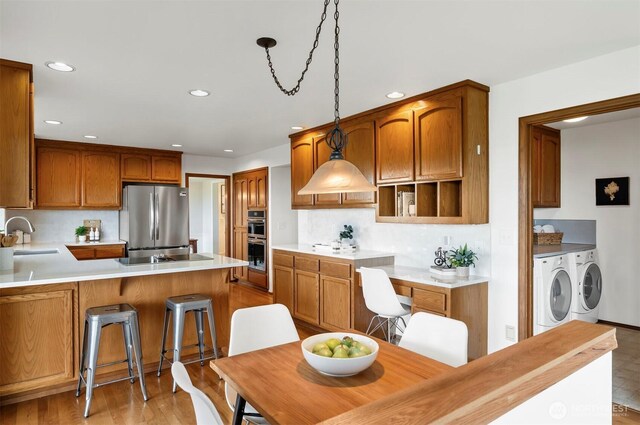 kitchen with recessed lighting, a peninsula, washing machine and clothes dryer, and stainless steel appliances