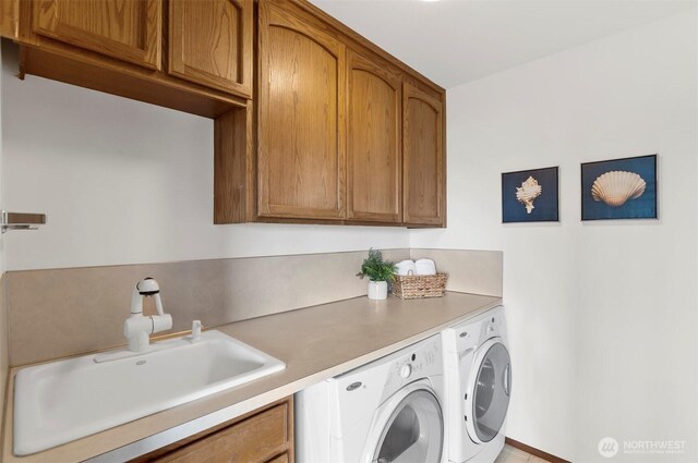 clothes washing area featuring washer and dryer, a sink, and cabinet space