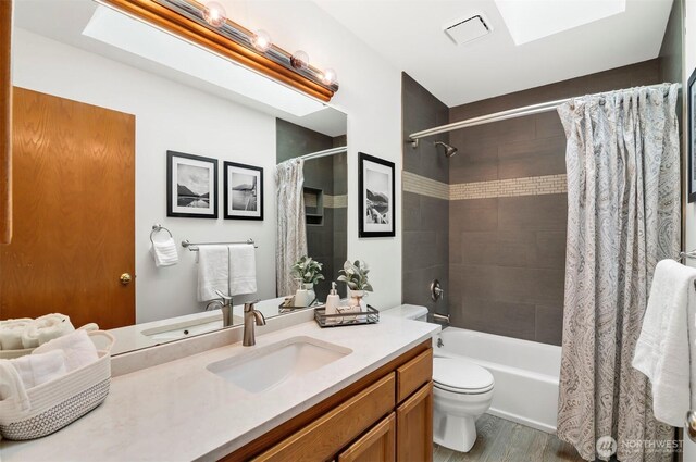 full bathroom featuring vanity, shower / tub combo with curtain, toilet, wood finished floors, and visible vents