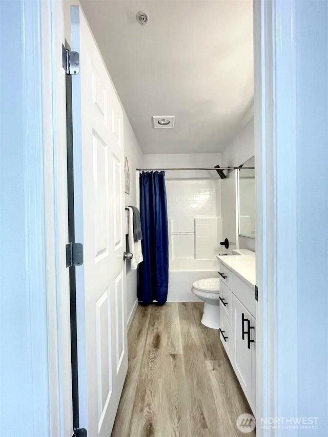 bathroom with shower / tub combo, wood finished floors, vanity, and toilet