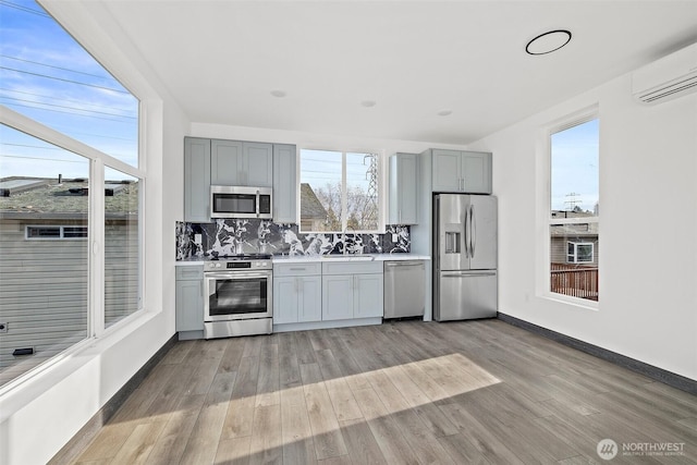 kitchen with light wood-style floors, light countertops, stainless steel appliances, and a wall mounted air conditioner