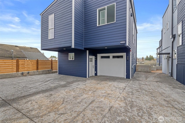 exterior space with fence, an attached garage, and driveway