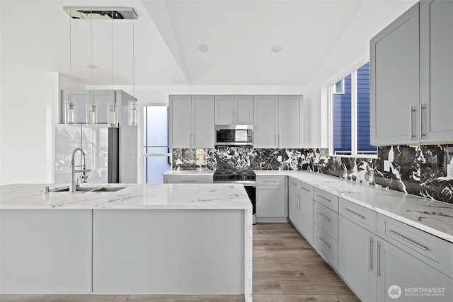 kitchen with a sink, light stone counters, tasteful backsplash, and stainless steel appliances