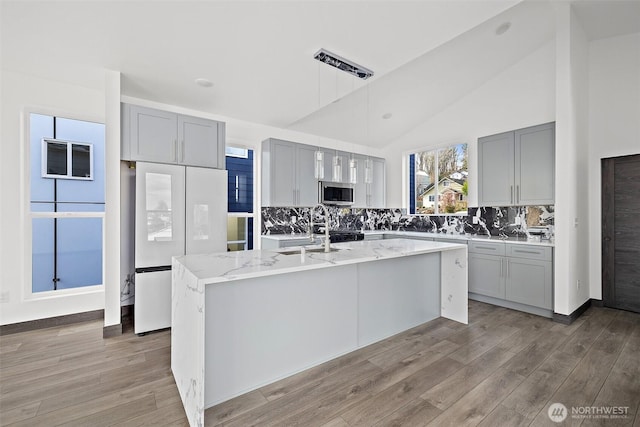 kitchen with gray cabinetry, freestanding refrigerator, light wood finished floors, and a sink