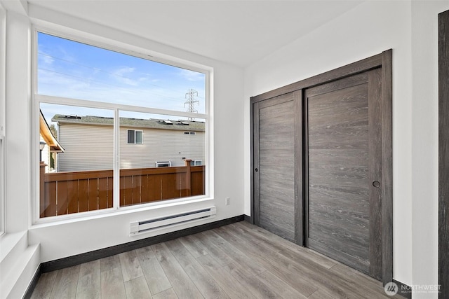 unfurnished sunroom with a baseboard heating unit