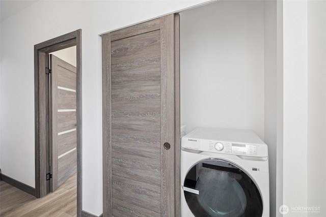 washroom with laundry area, baseboards, washer / clothes dryer, and wood finished floors