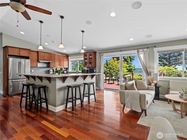 17111 NE 5th St, Bellevue, WA 98008 - kitchen with freestanding refrigerator, brown cabinets, a breakfast bar, under cabinet range hood, and dark wood-style floors