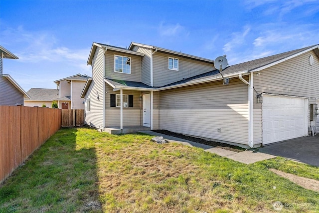 rear view of house with a lawn, a garage, fence, and driveway