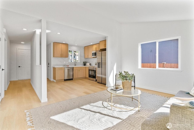 living room with light wood-style floors, recessed lighting, and baseboards