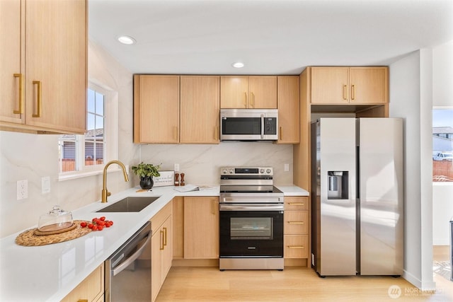 kitchen featuring a sink, appliances with stainless steel finishes, and light brown cabinetry