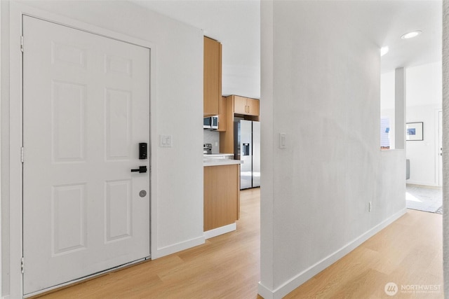 hall with baseboards and light wood finished floors