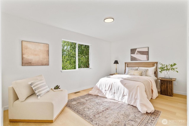 bedroom featuring baseboards, wood finished floors, and visible vents