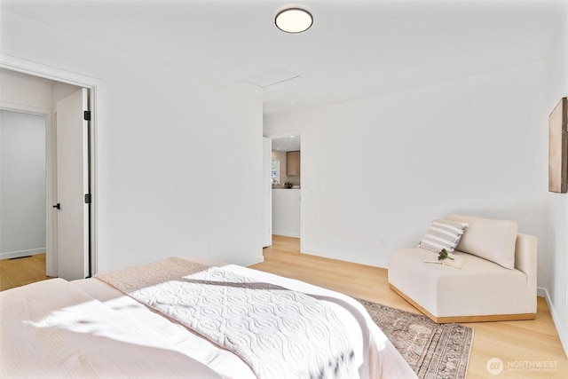 bedroom with baseboards, attic access, and wood finished floors
