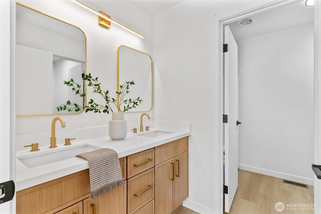 bathroom featuring double vanity, visible vents, a sink, and wood finished floors